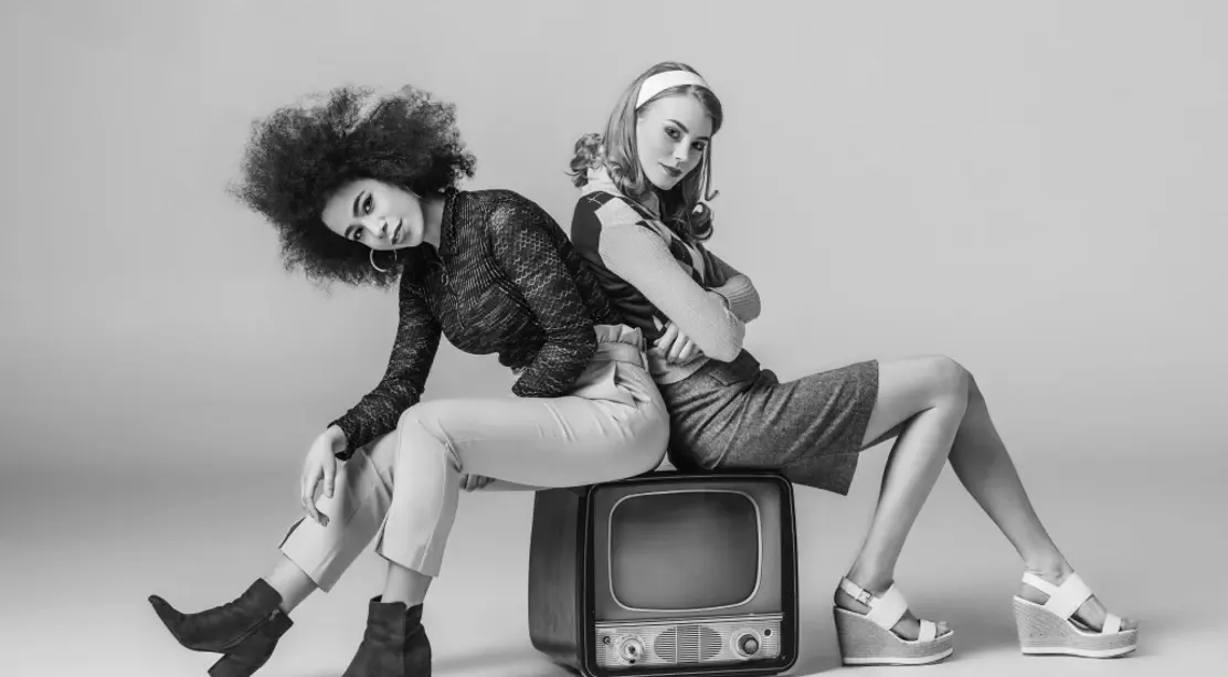 retro televizyon üzerinde oturan iki kişinin siyah beyaz moda fotoğrafı