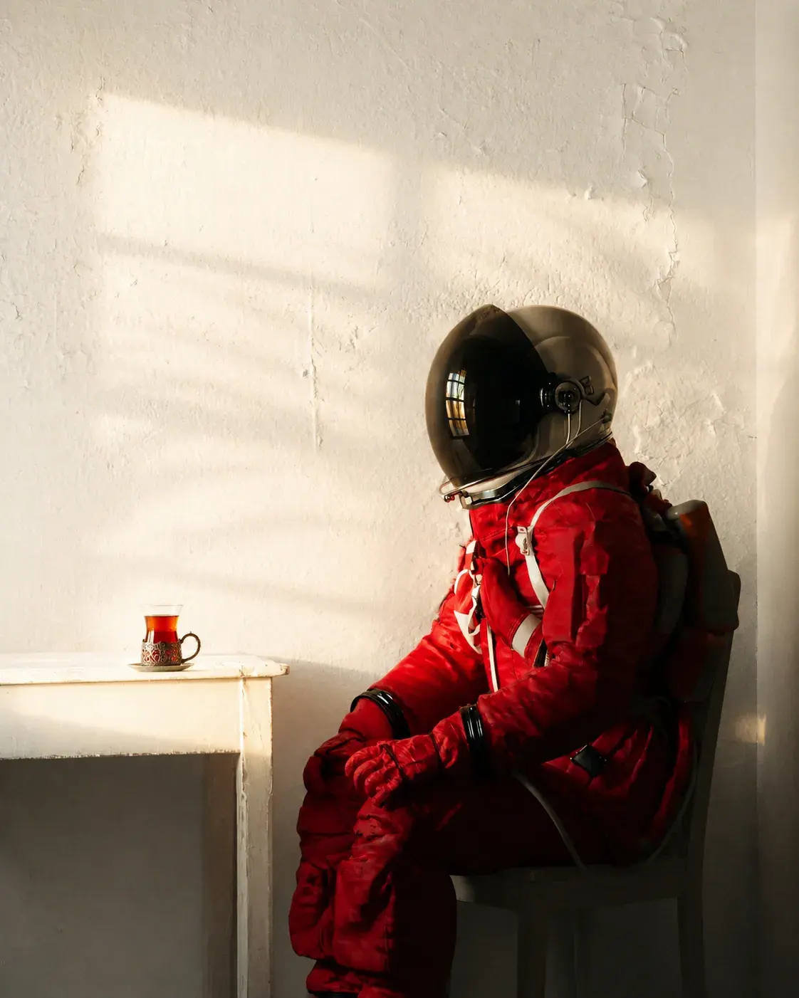 kırmızı astronot kıyafeti giymiş, yanında bir bardak çay olan figür